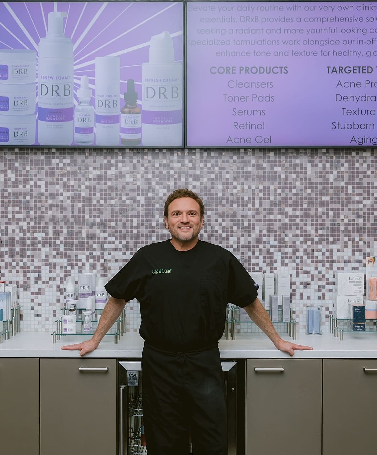 Skincare professional in clinic with product display.