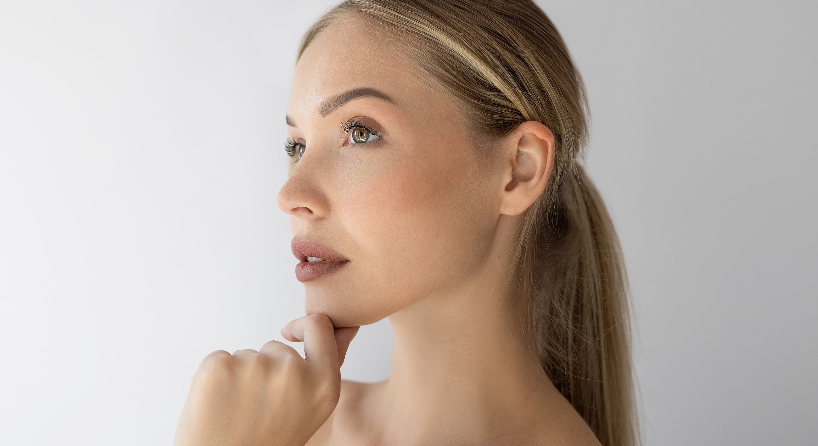 Thoughtful woman with hand on chin, side profile.