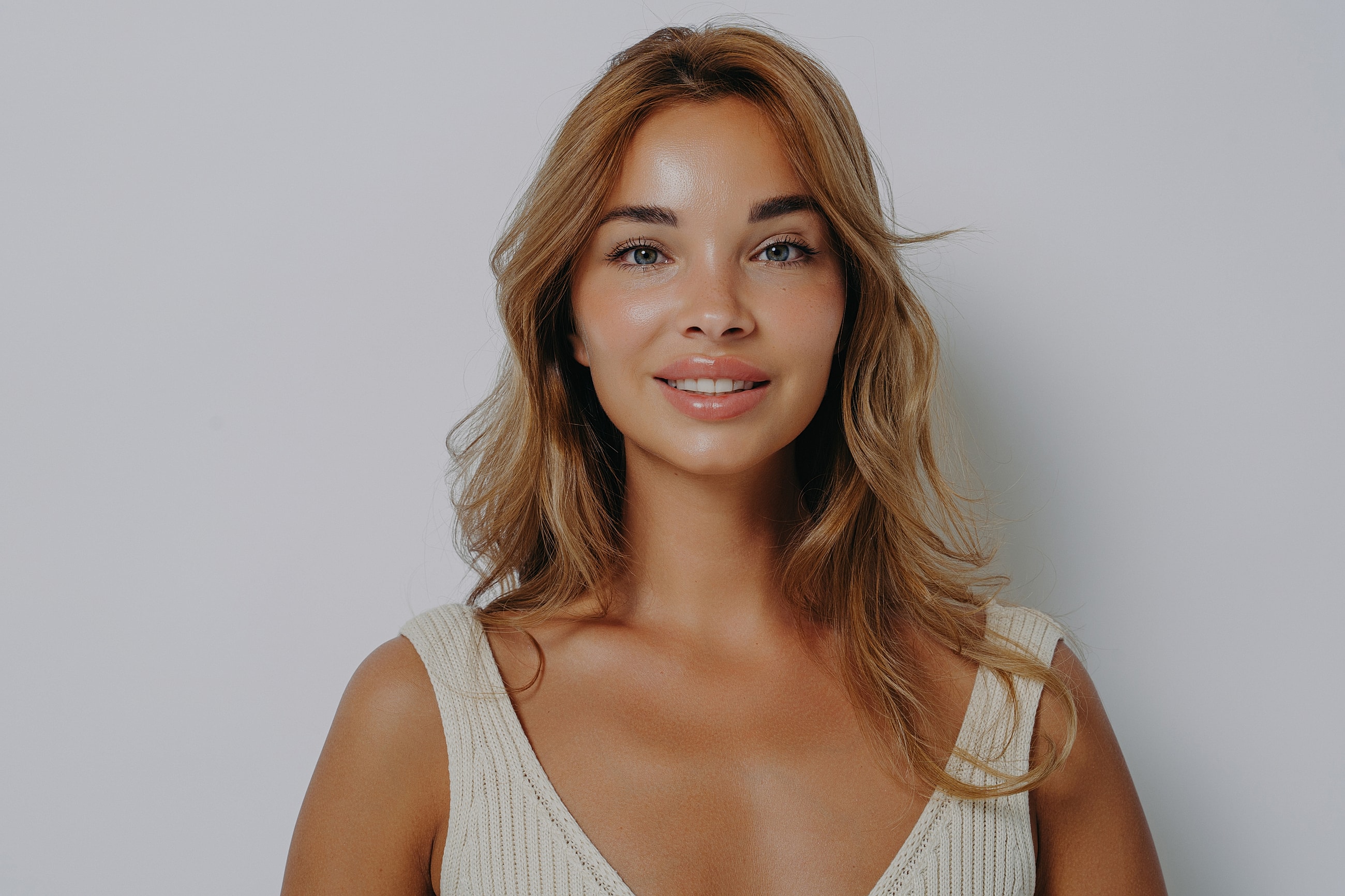 Smiling woman with wavy hair against plain background.