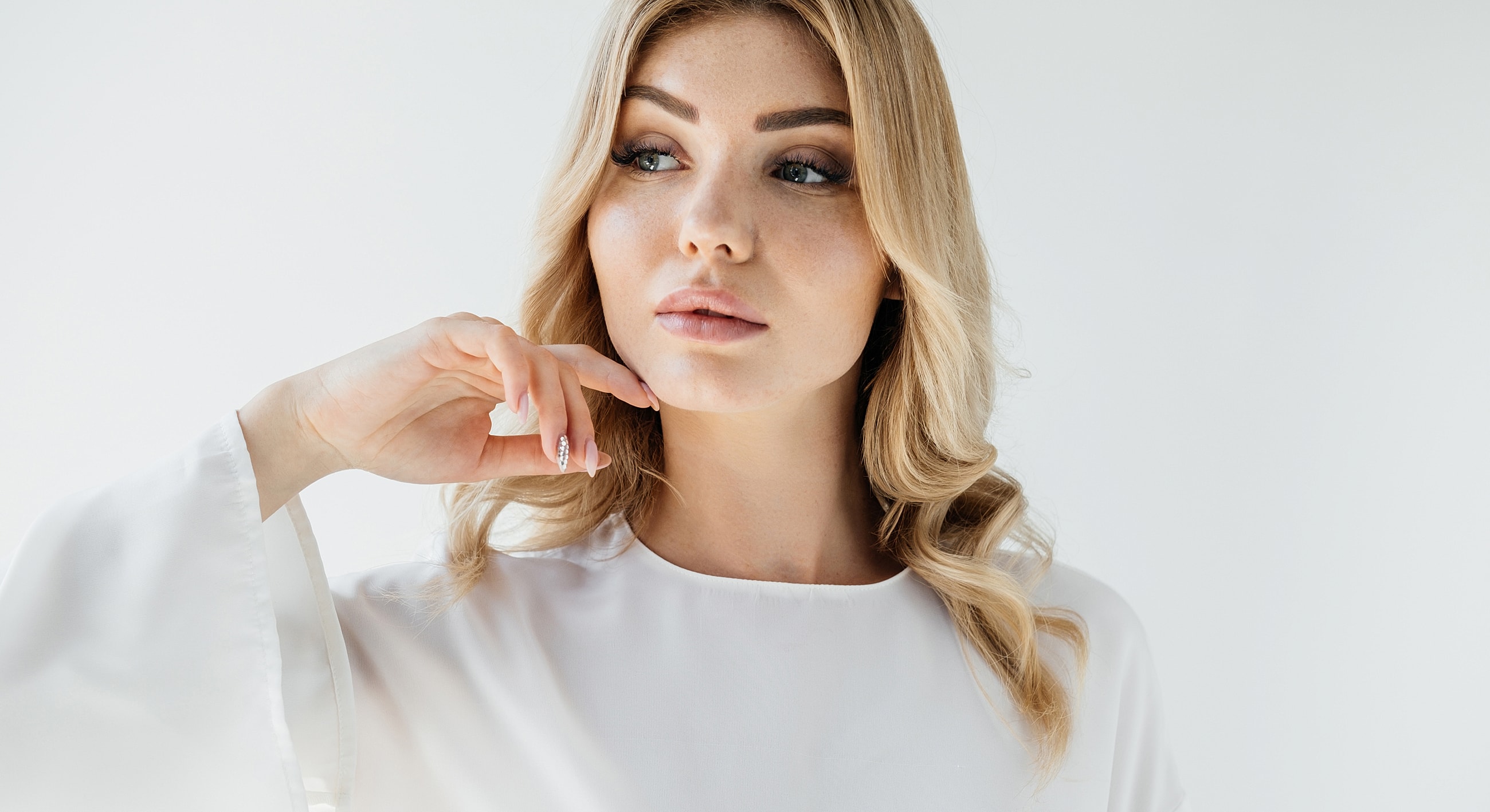 Woman in white outfit with thoughtful expression.